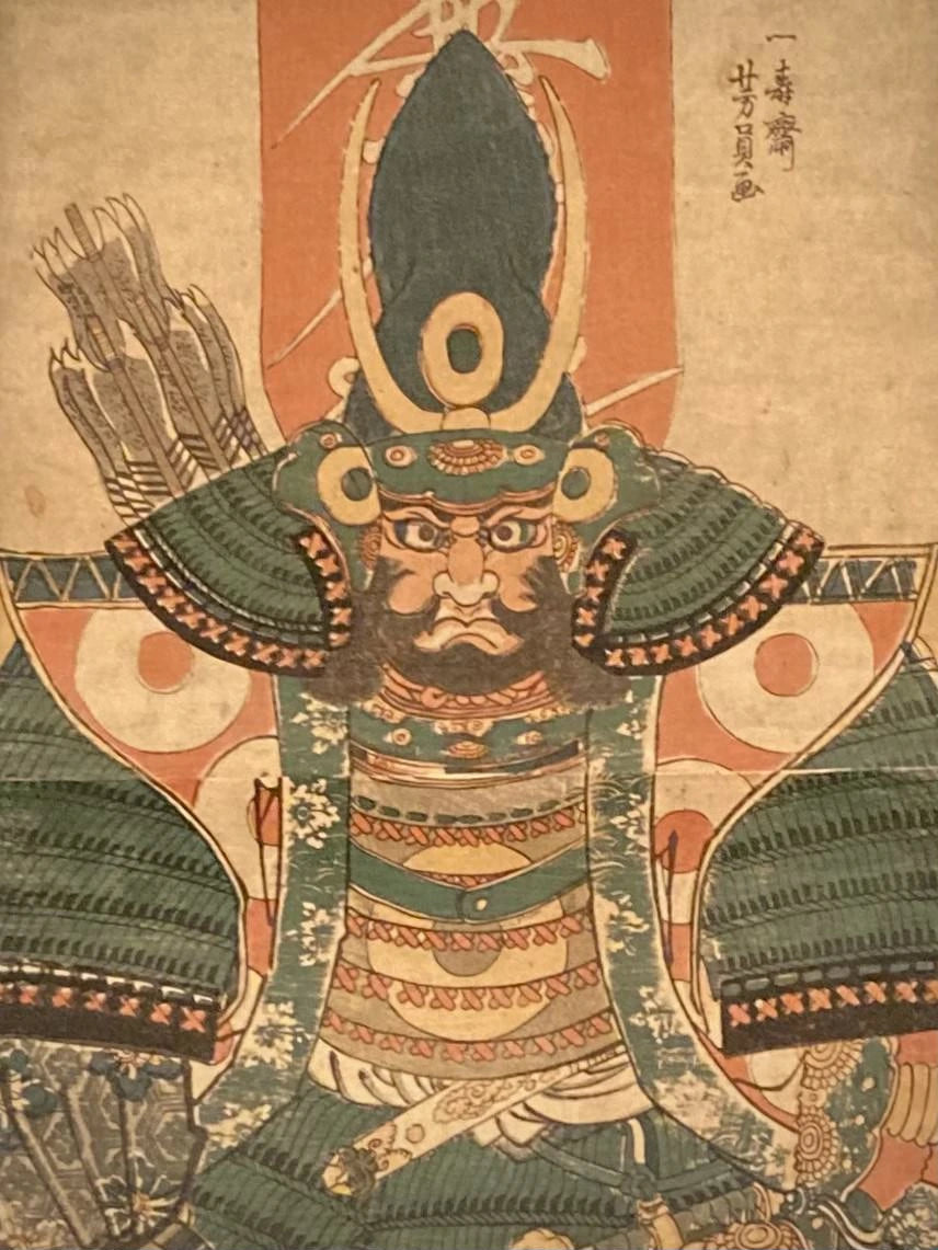 Close-up of Utagawa Yoshikazu’s samurai print showing ornate armor, textured helmet details, and stern facial features in rich red and green tones.