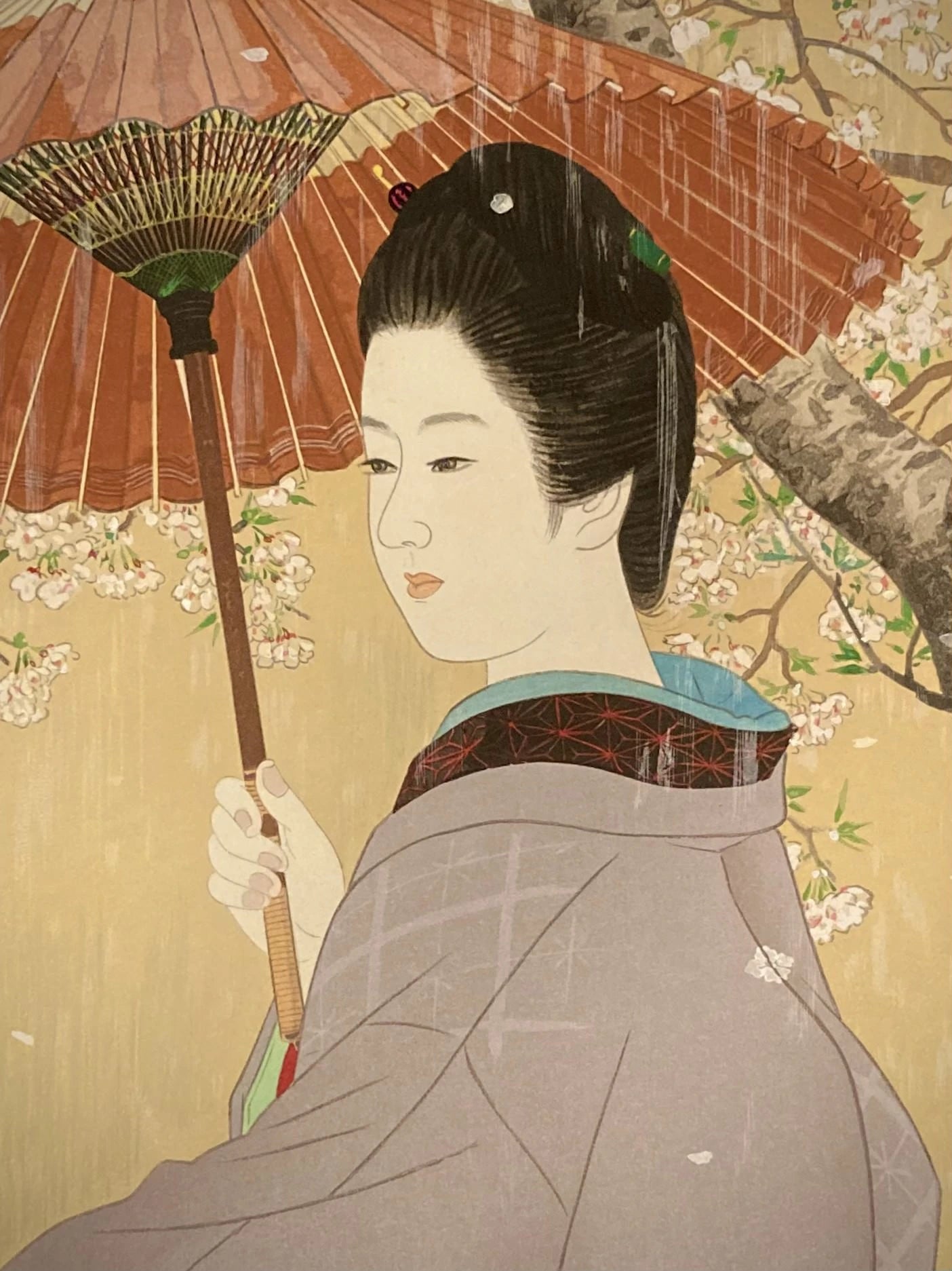 Close-up of a Japanese art print showing the detailed red umbrella, falling sakura petals, and soft facial expression of a woman in spring rain by Ito Shinsui.