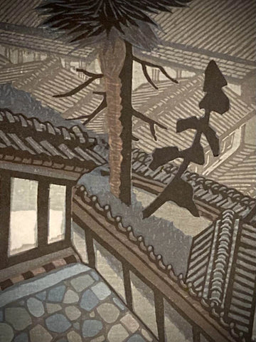 Close-up of Japanese art print by Junichiro Sekino showing tiled rooftops and evergreen tree detail, highlighting geometric precision in a serene townscape.