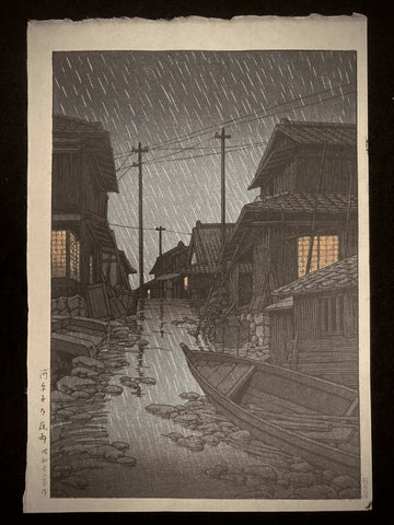 Traditional Japanese rain-soaked alley at night with wooden houses and glowing windows by Kawase Hasui.