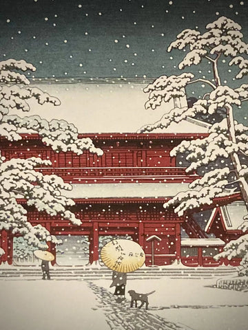 Close-up of Japanese art print by Kawase Hasui showing snow-dusted red temple gate and falling snowflakes, with figure holding umbrella on winter path.