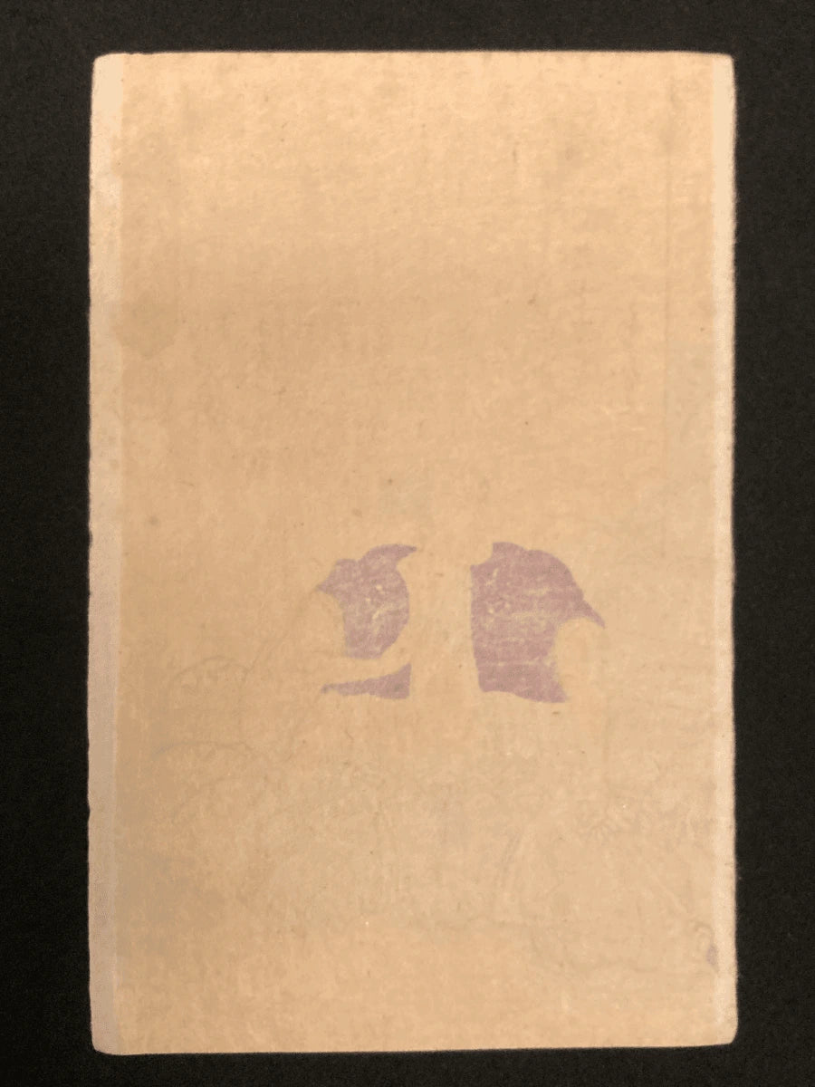 Rear view of the samurai’s seated form, showing the drape of his haori and hakama, his tied topknot, and minimal background with a low stone marker.