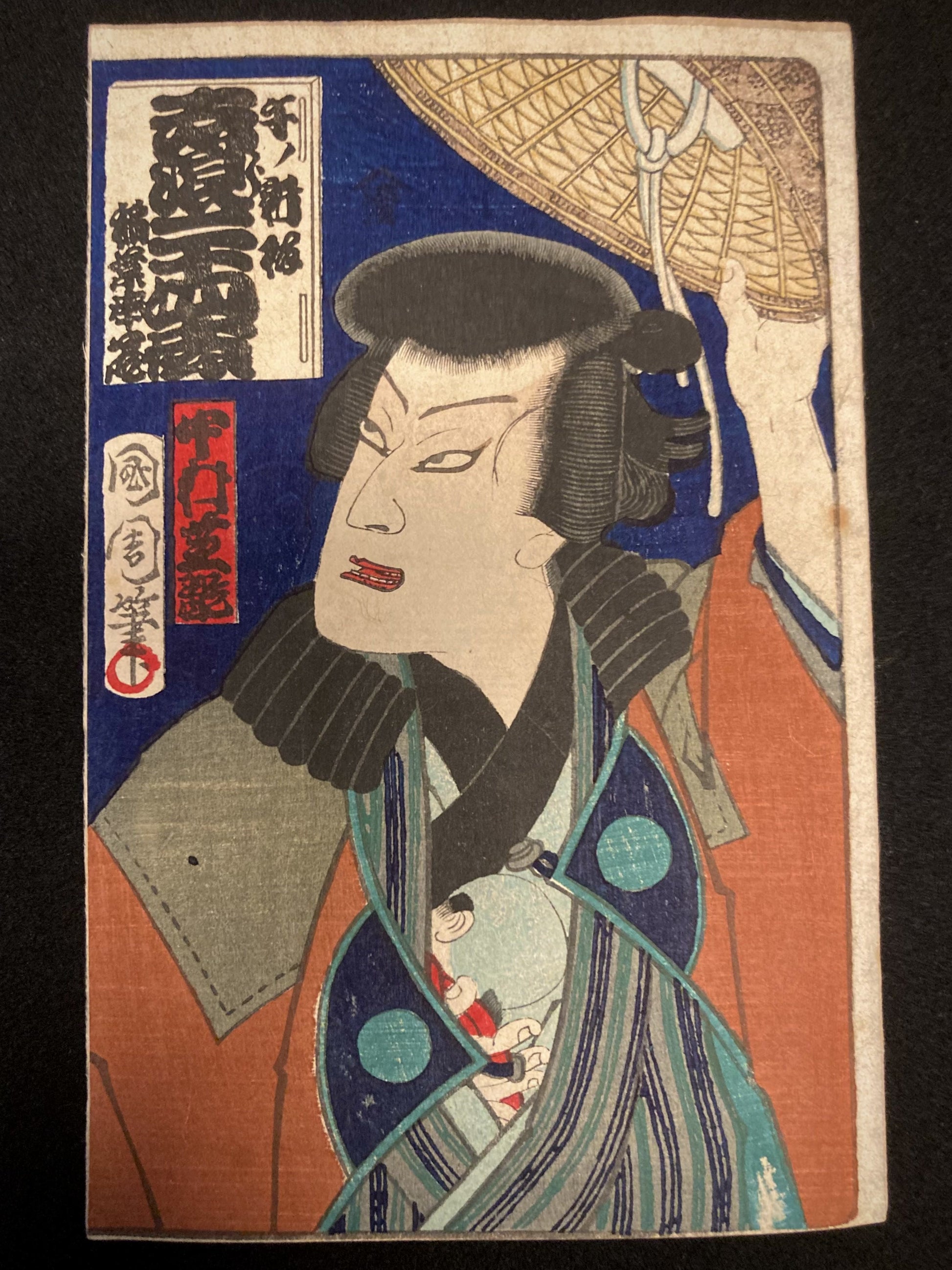 Front view of Toyohara Kunichika’s ukiyo-e print featuring kabuki actor Nakamura Shikan holding a woven kasa hat, set against a dark backdrop.