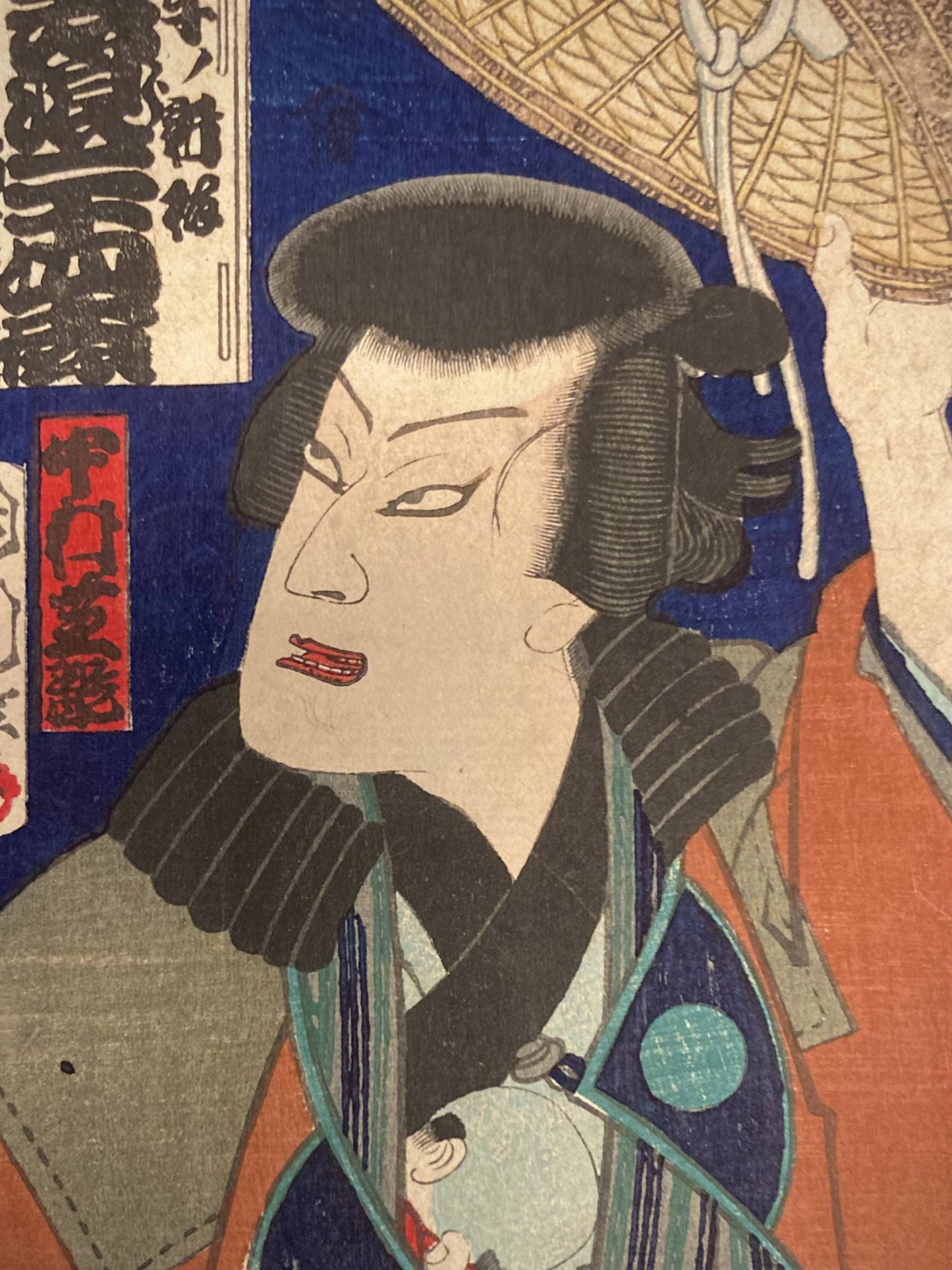 Close-up of Nakamura Shikan’s focused expression beneath a raised kasa hat, showcasing detailed facial lines, fabric textures, and dramatic flair.
