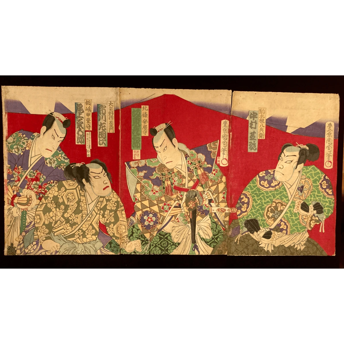 Full triptych ukiyo-e print by Kunichika showing four samurai in ornate kimonos set against a vivid red background, exuding theatrical tension.