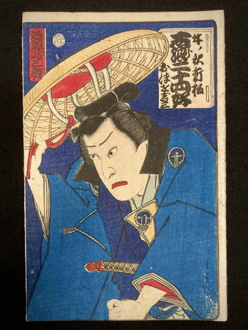 Japanese woodblock print by Toyohara Kunichika showing a Kabuki actor adjusting a large straw hat, wearing a dark blue kimono against a dramatic deep blue background.