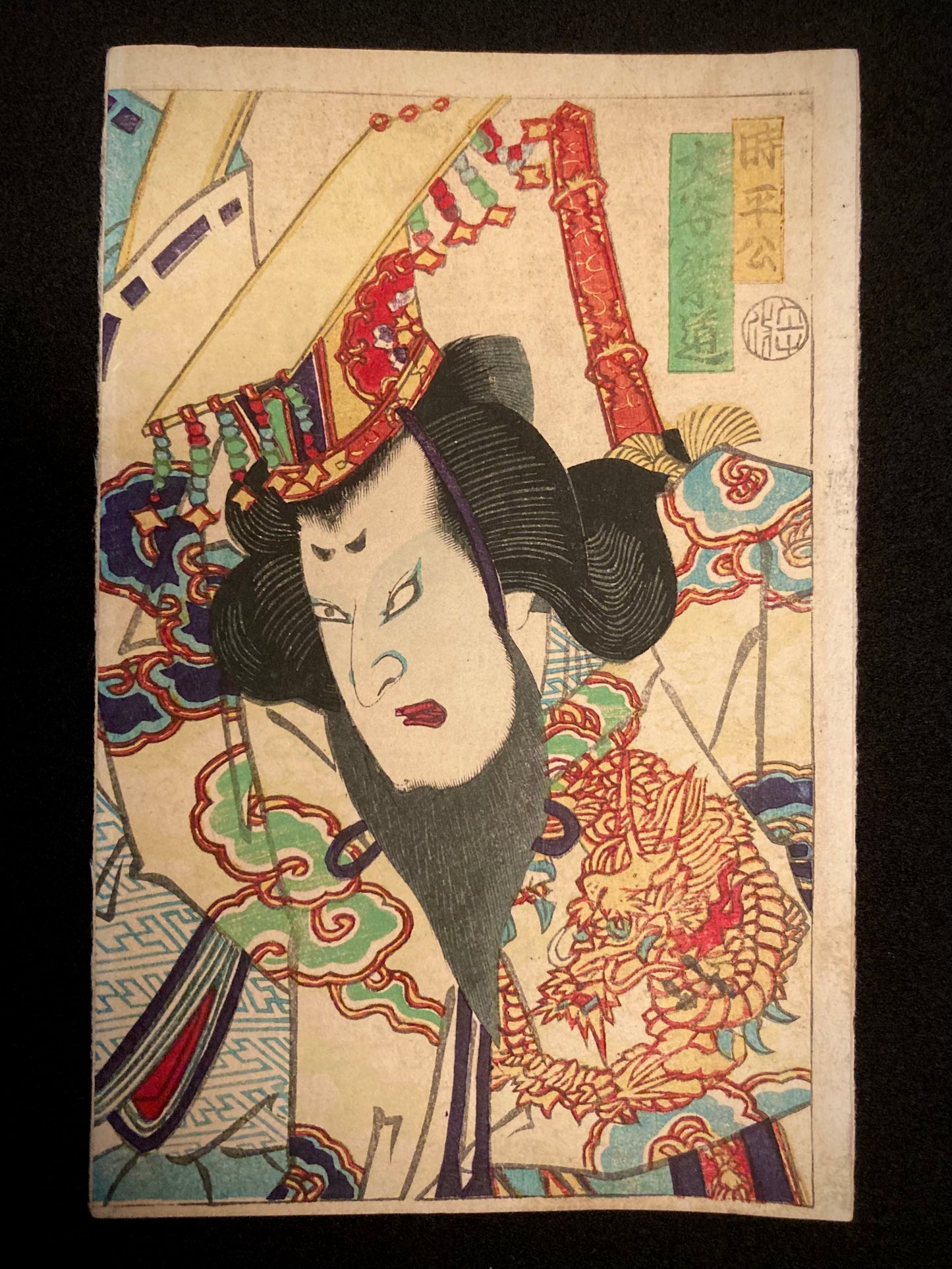 Japanese woodblock print of a Kabuki actor in ornate robes with a dragon motif and a dramatic expression, set against swirling clouds in classic Ukiyo-e style.