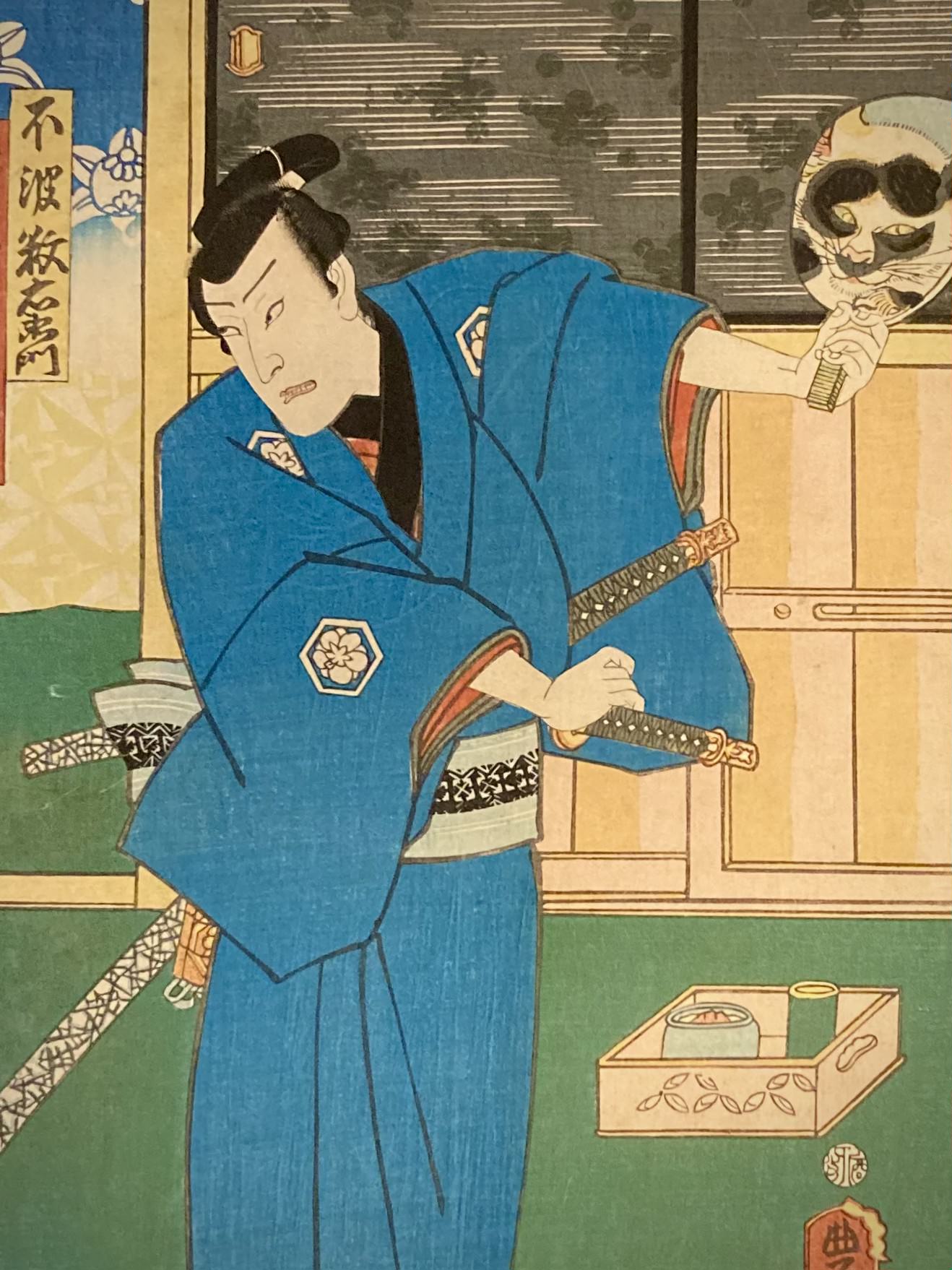 Close-up of a samurai’s intense gaze into a mirror reflecting a cat’s face. Rich blue kimono and sword details highlight Kunisada’s expressive style.