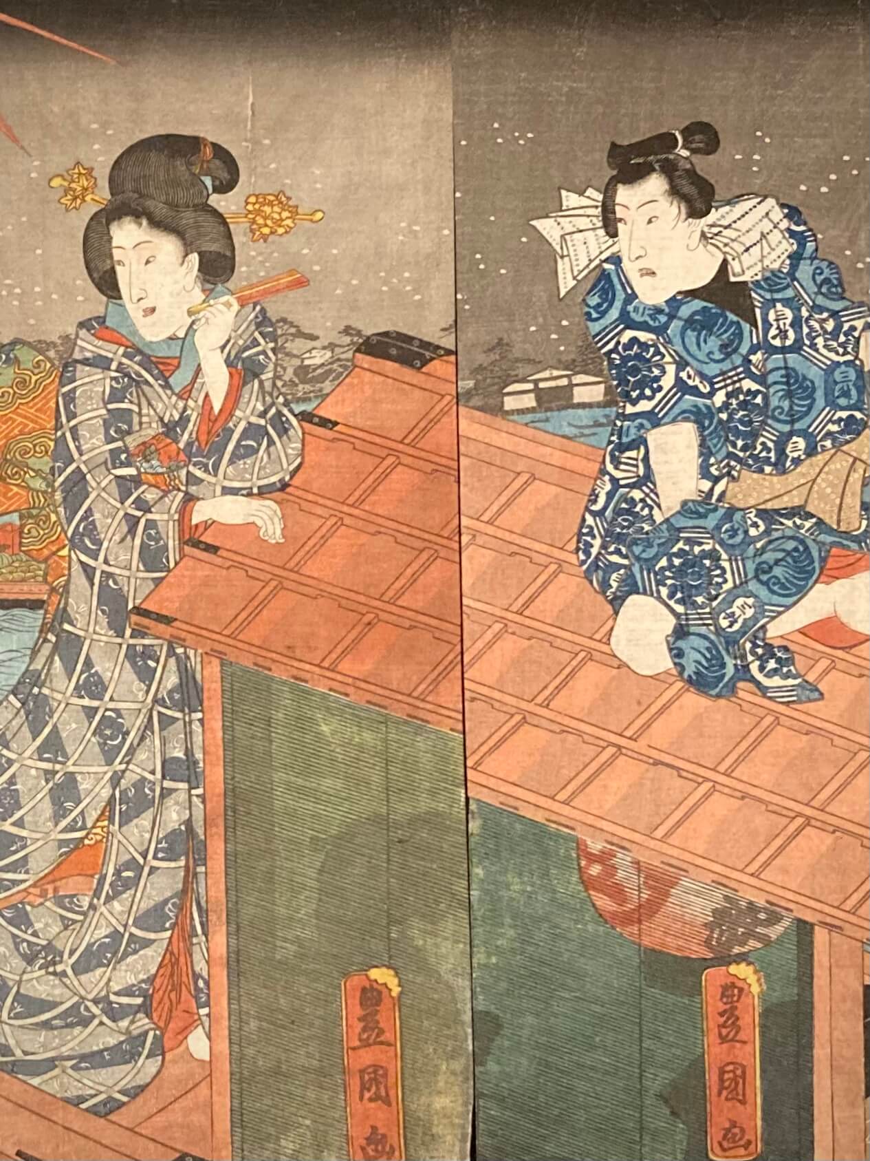 Close-up of Utagawa Kunisada’s ukiyo-e print showing detailed kimono patterns and subtle facial expressions as fireworks glow in the sky.